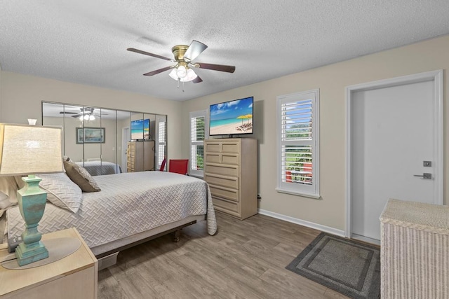 bedroom featuring a textured ceiling, wood finished floors, a ceiling fan, and baseboards