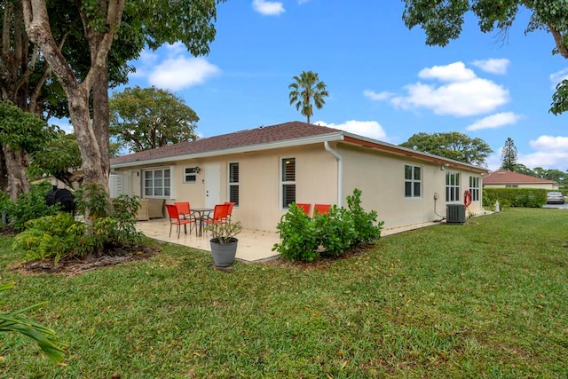 rear view of house with a patio, central air condition unit, a lawn, and stucco siding