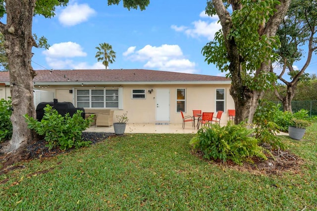 rear view of house featuring fence, a patio, a lawn, and stucco siding