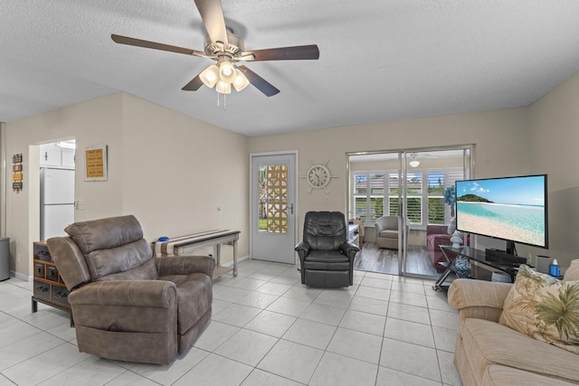 living room featuring a ceiling fan, a textured ceiling, baseboards, and light tile patterned floors