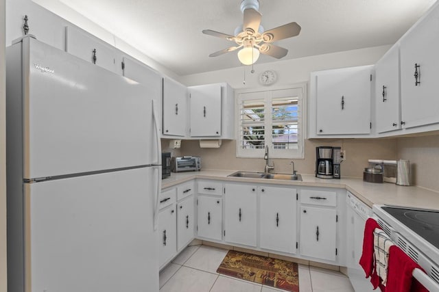 kitchen featuring light tile patterned floors, light countertops, white cabinets, a sink, and white appliances