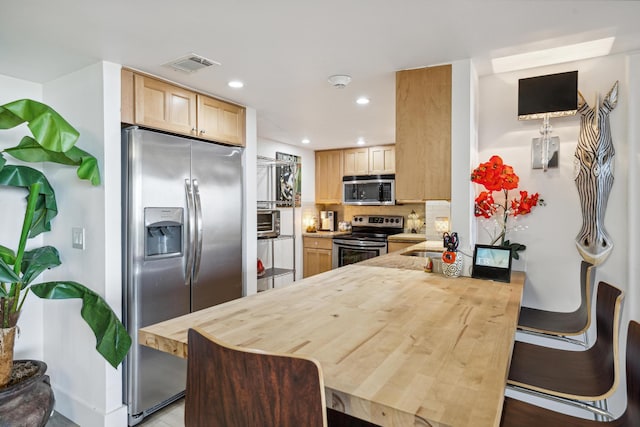 kitchen with kitchen peninsula, backsplash, sink, stainless steel appliances, and light brown cabinetry