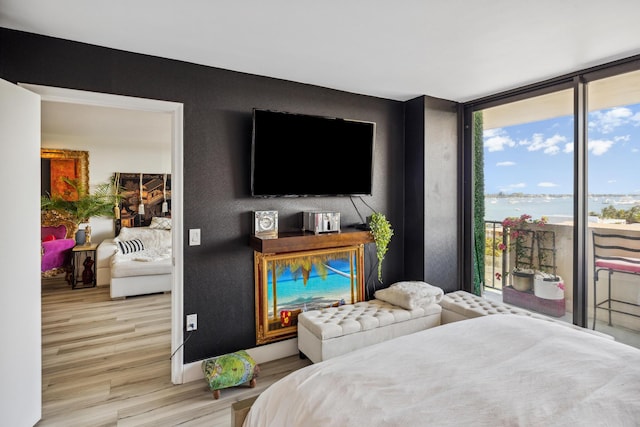 bedroom with floor to ceiling windows, light hardwood / wood-style flooring, access to exterior, and multiple windows