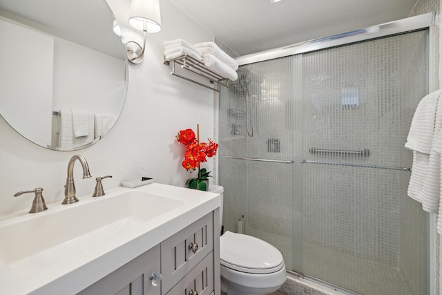 bathroom with vanity, a shower with door, and toilet