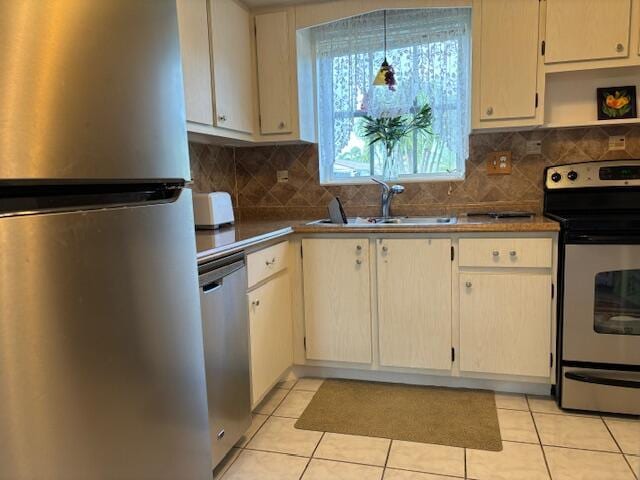 kitchen featuring stainless steel appliances, tasteful backsplash, decorative light fixtures, light tile patterned flooring, and sink