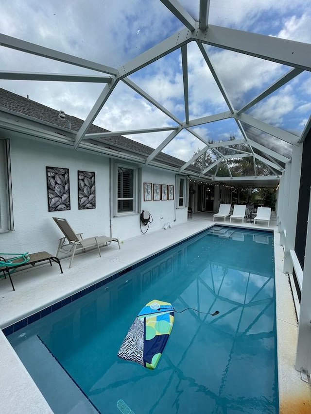 view of swimming pool featuring glass enclosure and a patio