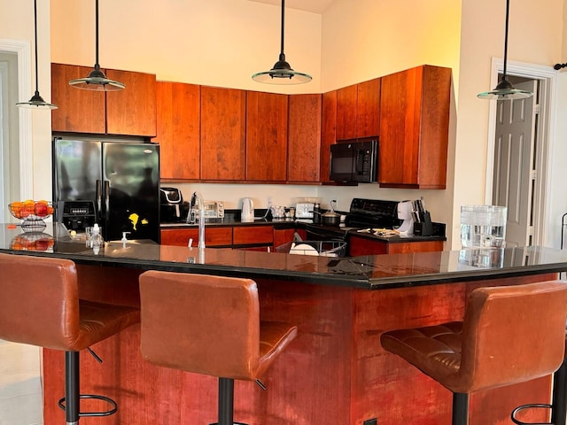 kitchen featuring decorative light fixtures, a breakfast bar, and black appliances