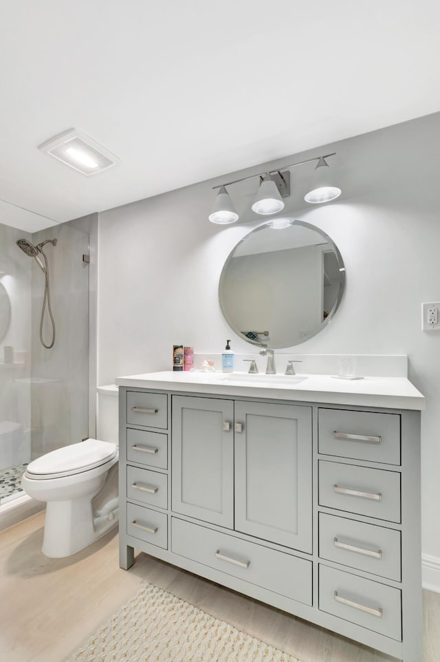 bathroom with vanity, tiled shower, hardwood / wood-style flooring, and toilet