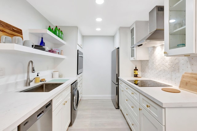 kitchen featuring wall chimney range hood, white cabinets, sink, light hardwood / wood-style floors, and stainless steel appliances