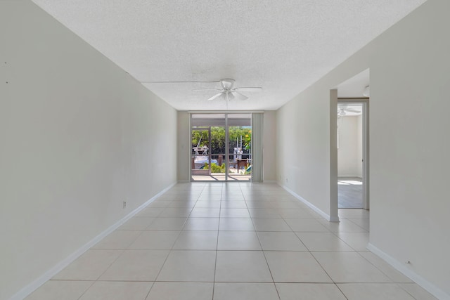 tiled spare room featuring a wall of windows, ceiling fan, and a textured ceiling