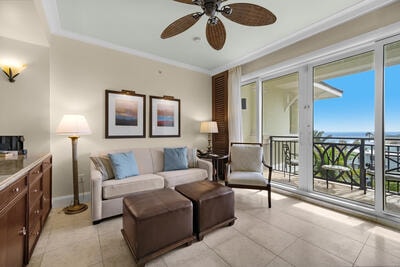 tiled living room with ceiling fan and ornamental molding