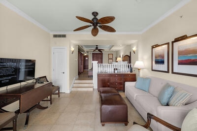 tiled living room with ceiling fan and ornamental molding