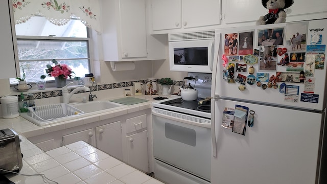 22 Northampton A, West Palm Beach, FL 33417 - kitchen with white appliances, tile counters, white cabinets, and a sink
