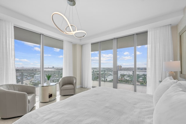 bedroom featuring access to exterior, light hardwood / wood-style floors, expansive windows, and a chandelier