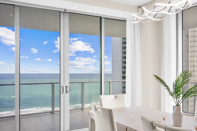 dining space featuring a chandelier, a water view, and a view of the beach