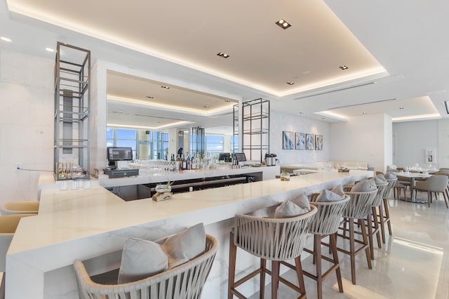 kitchen with a tray ceiling, kitchen peninsula, and a kitchen bar