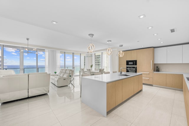 kitchen with a water view, a healthy amount of sunlight, an inviting chandelier, white cabinets, and hanging light fixtures