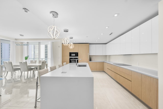 kitchen featuring white cabinetry, black appliances, hanging light fixtures, a notable chandelier, and a large island