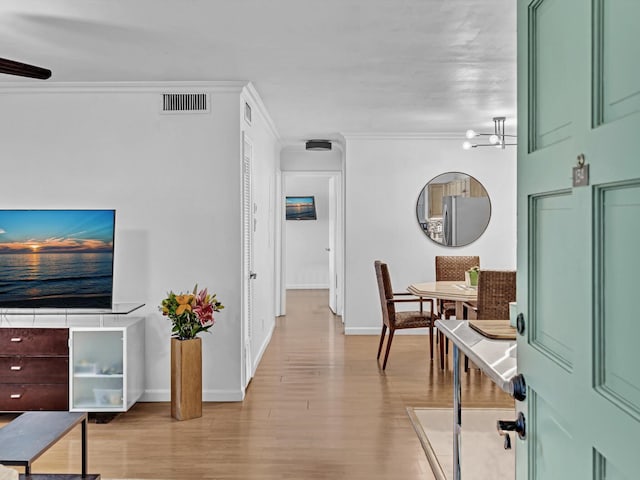 interior space featuring ornamental molding, a notable chandelier, and light hardwood / wood-style flooring