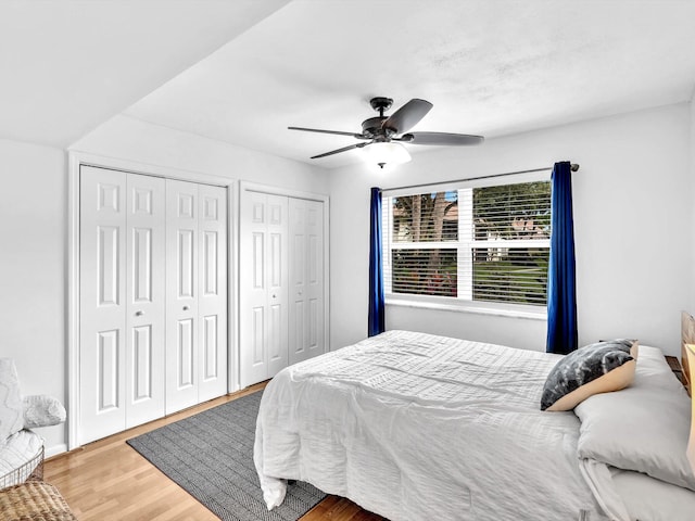 bedroom featuring two closets, ceiling fan, and light wood-type flooring