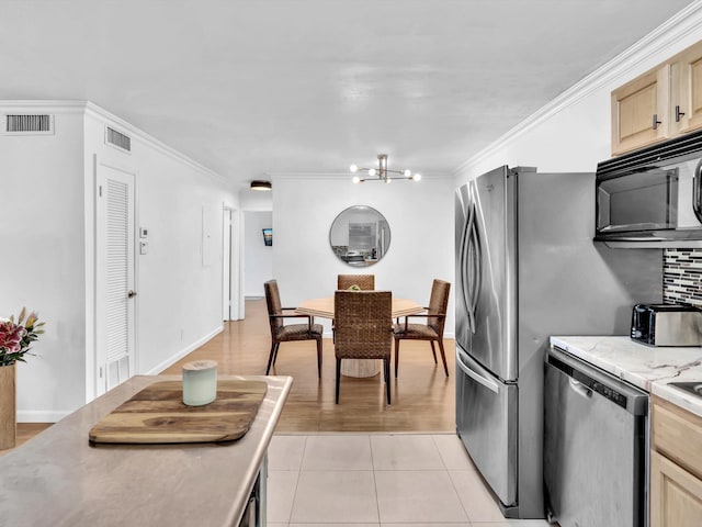 kitchen with a chandelier, light brown cabinets, stainless steel appliances, light tile floors, and ornamental molding