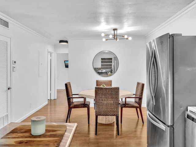 dining room with a chandelier, ornamental molding, and light hardwood / wood-style floors