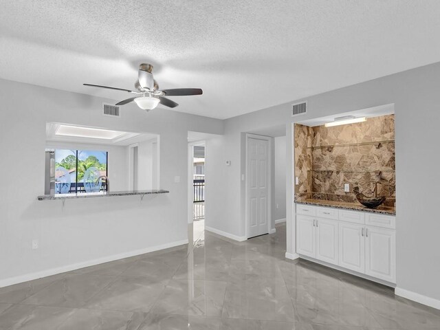 unfurnished living room featuring a textured ceiling and ceiling fan