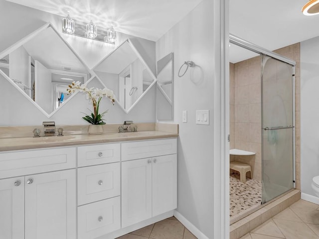 bathroom with a shower with door, vanity, toilet, and tile patterned floors