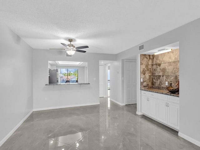 unfurnished living room with ceiling fan and a textured ceiling