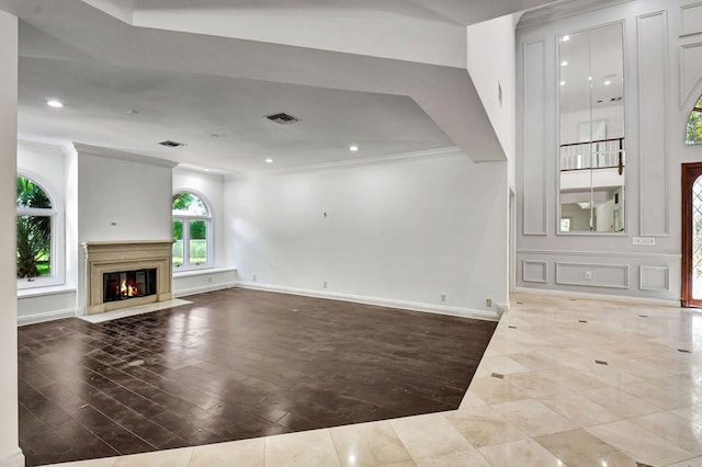 unfurnished living room with hardwood / wood-style floors, ornamental molding, and a premium fireplace