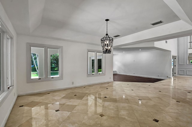 unfurnished living room with an inviting chandelier and a tray ceiling