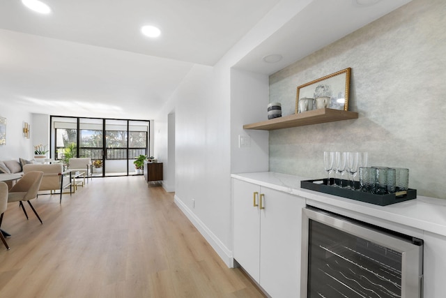 kitchen featuring light hardwood / wood-style floors, expansive windows, white cabinetry, and wine cooler