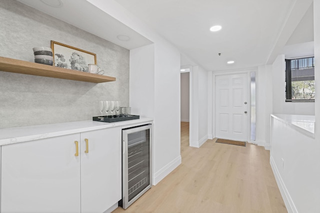 kitchen with white cabinets, beverage cooler, and light wood-type flooring