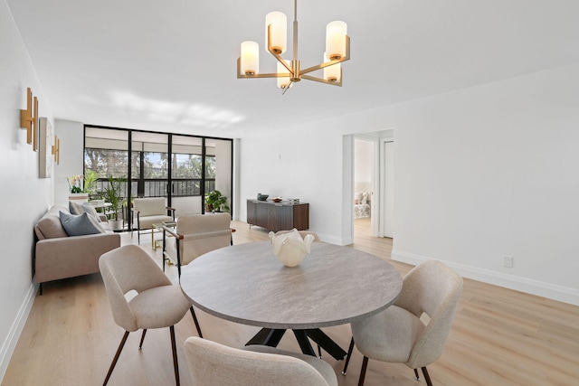 dining space featuring an inviting chandelier, light hardwood / wood-style floors, and expansive windows