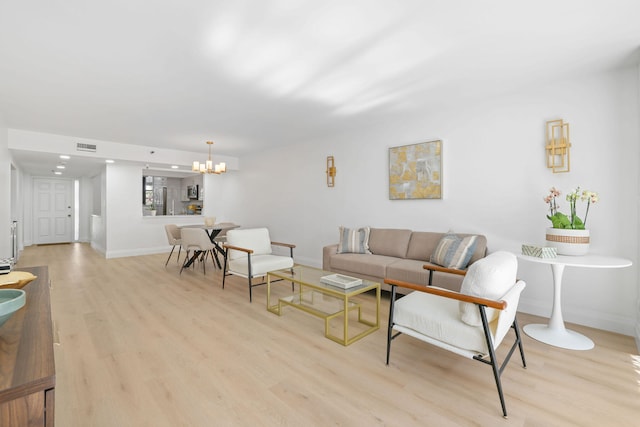 living room with light hardwood / wood-style floors and an inviting chandelier