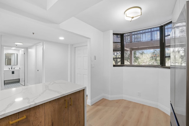 kitchen featuring light hardwood / wood-style flooring, sink, and light stone counters