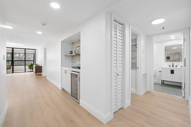 corridor with wine cooler, sink, and light hardwood / wood-style flooring