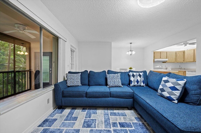 living room with a textured ceiling and ceiling fan with notable chandelier