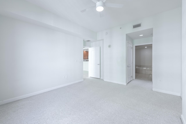 unfurnished bedroom featuring connected bathroom, light colored carpet, and ceiling fan