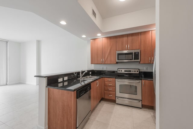 kitchen with sink, stainless steel appliances, kitchen peninsula, dark stone countertops, and light tile patterned floors