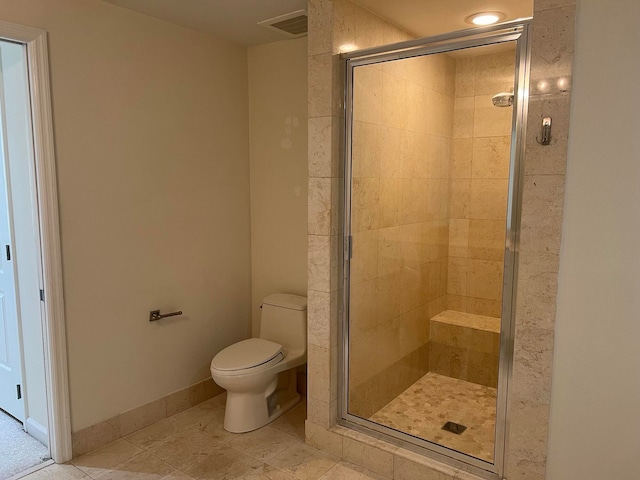 bathroom featuring tile patterned flooring, toilet, and an enclosed shower