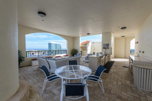 view of patio / terrace featuring sink, a water view, and an outdoor kitchen