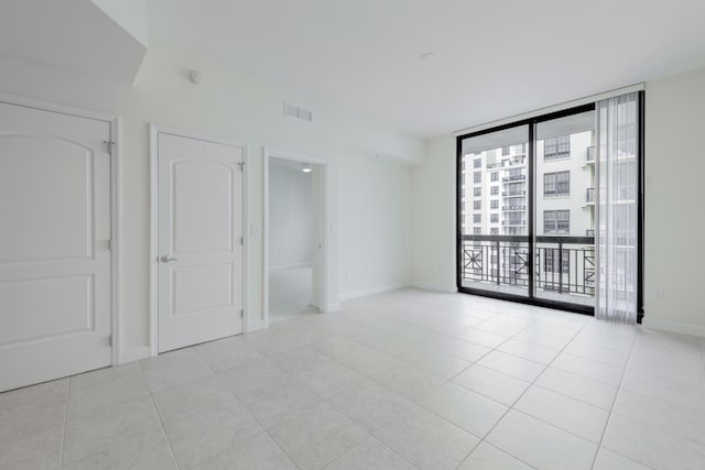 empty room with floor to ceiling windows and light tile patterned floors