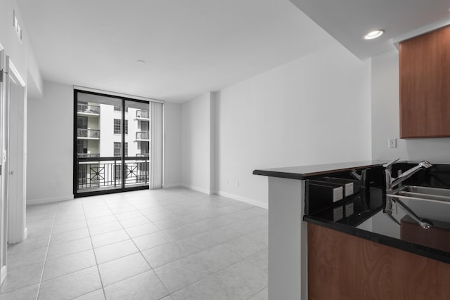 kitchen featuring light tile patterned flooring, kitchen peninsula, expansive windows, and sink