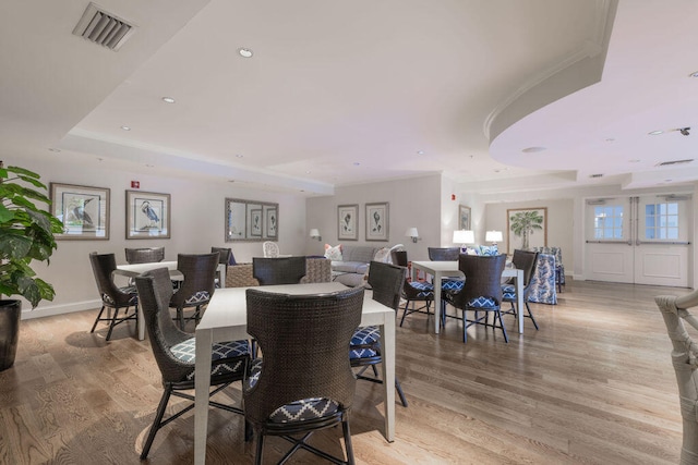 dining room featuring a tray ceiling and light hardwood / wood-style floors