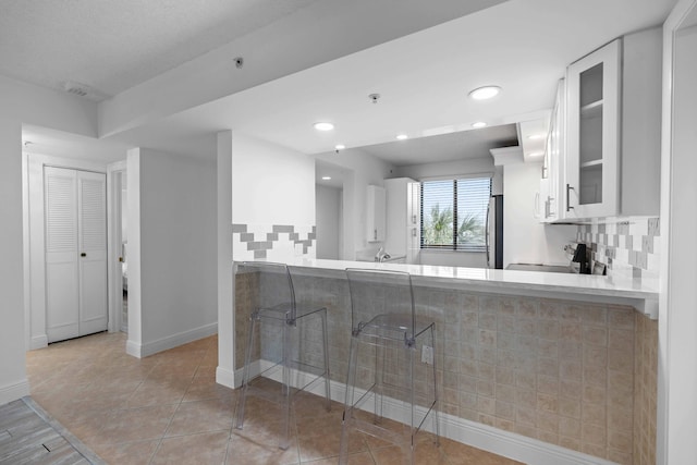 kitchen with light tile floors, white cabinetry, and kitchen peninsula