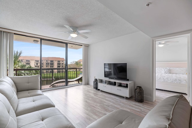 living room featuring a textured ceiling, light hardwood / wood-style floors, ceiling fan, and floor to ceiling windows