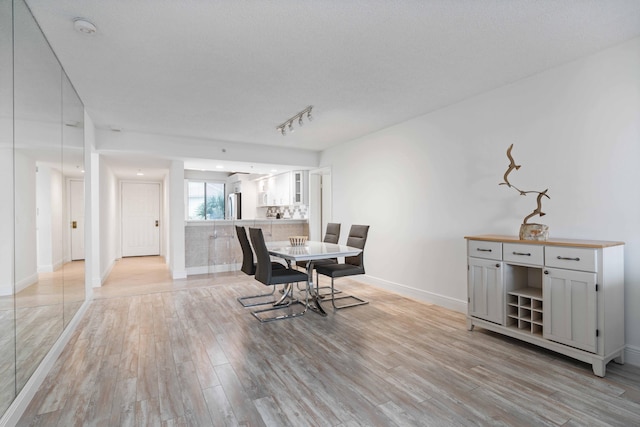 dining room featuring a textured ceiling, track lighting, and light wood-type flooring