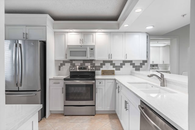 kitchen featuring sink, stainless steel appliances, white cabinets, and light tile floors