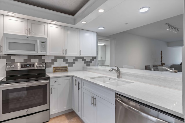 kitchen featuring light tile floors, white cabinets, appliances with stainless steel finishes, sink, and tasteful backsplash